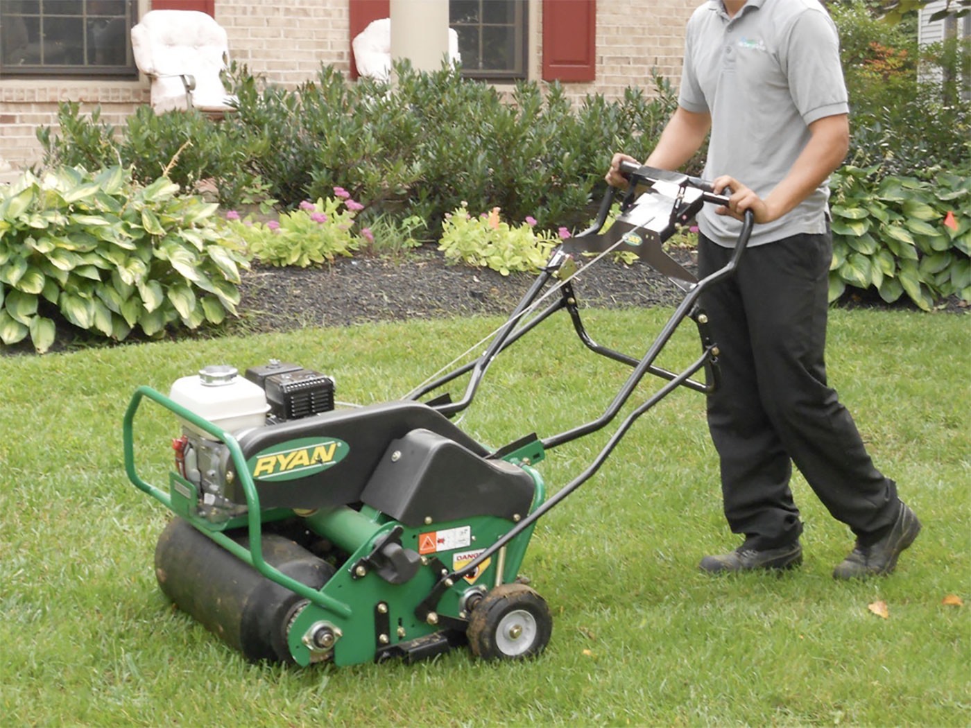 Man with gray shirt and black pants using the lawn mower